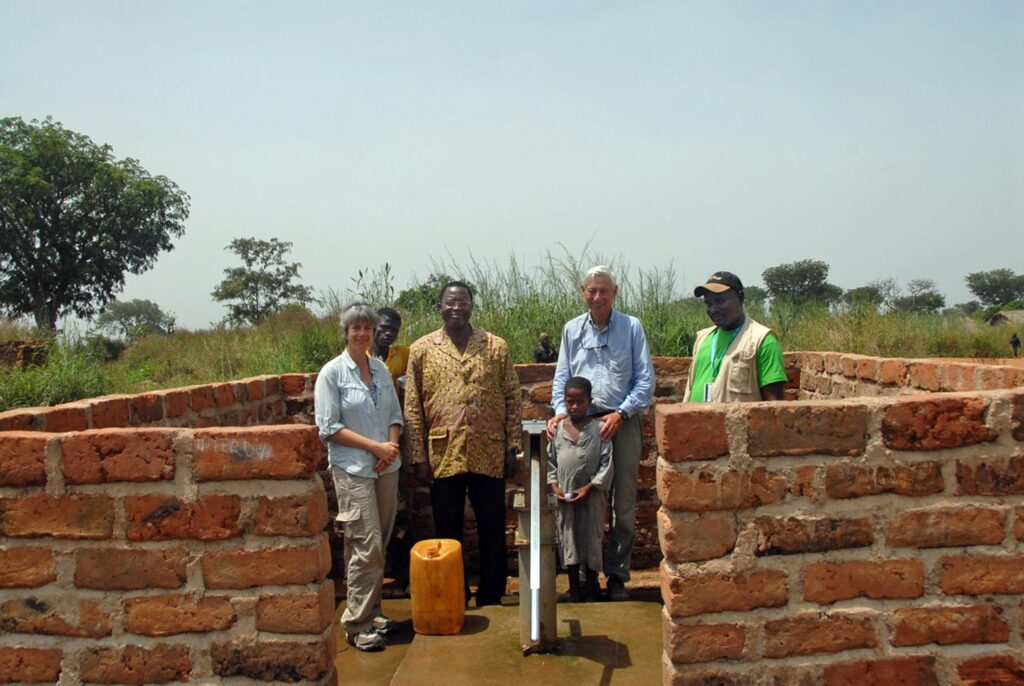 People standing around water pump